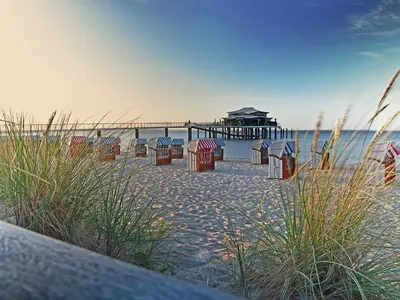 Wundervoller Sommermorgen am Strand mit Strandkorb und einer Seebrücke im sichten Ostsee-Wasser in Timmendorfer-Strand