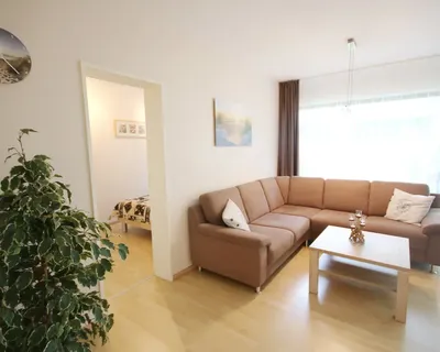 Das helle Wohnzimmer der Ferienwohnung Heimathafen in Timmendorfer-Strand Sofa und Wohnzimmertisch und mit dem Schlafzimmer im Nebenraum