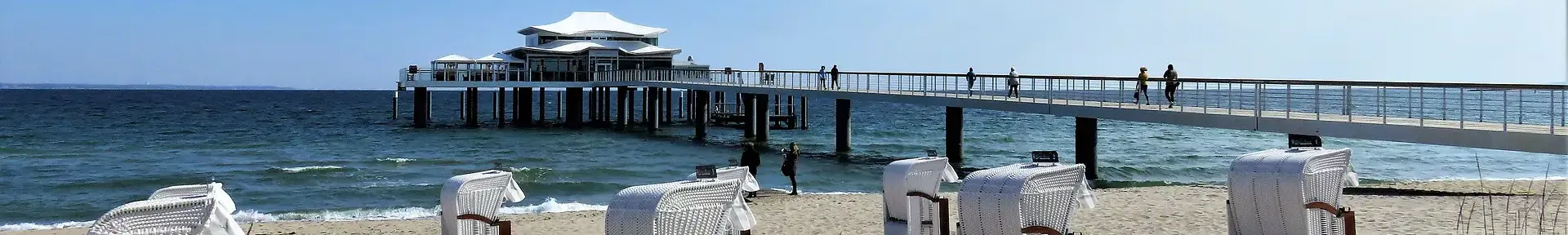 Strandkörbe und die Seebrücke vor Sonneuntergang bei ruhigem Wetter in Timmendorfer-Strand